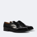 Pair of black leather dress shoes on a light gray background
